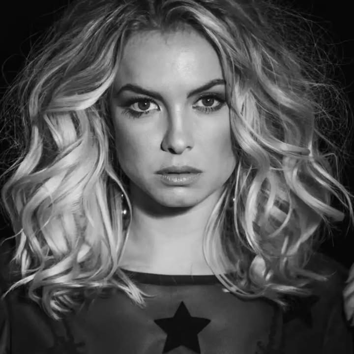 Imagem de Lua Blanco, atriz e cantora, em tom comovido, com expressão serena; possível foto de arquivo ou rara aparição pública.